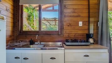 A kitchen with wooden walls, a window, a sink, a coffee maker, and cabinets.
