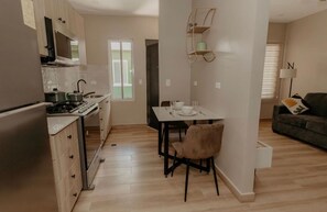A compact kitchen with a dining area, a sofa, and a lamp. - Premium Mountain View Apartment. (Alto Boquete)