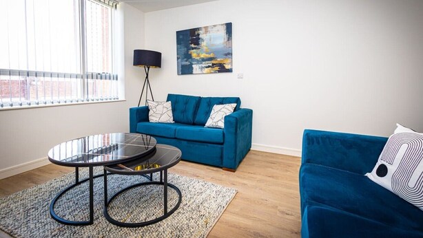 A modern living room with a blue sofa, a round coffee table, and a painting on the wall. - Birmingham City Retreat No 126 (Birmingham)
