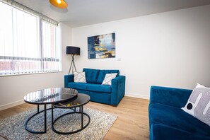 A modern living room with a blue sofa, a round coffee table, and a painting on the wall. - Birmingham City Retreat No 126 (Birmingham)