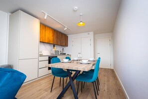 A compact kitchen with white cabinets, a wooden countertop, and a dining area with a table and chairs. - Birmingham City Retreat No 126 (Birmingham)