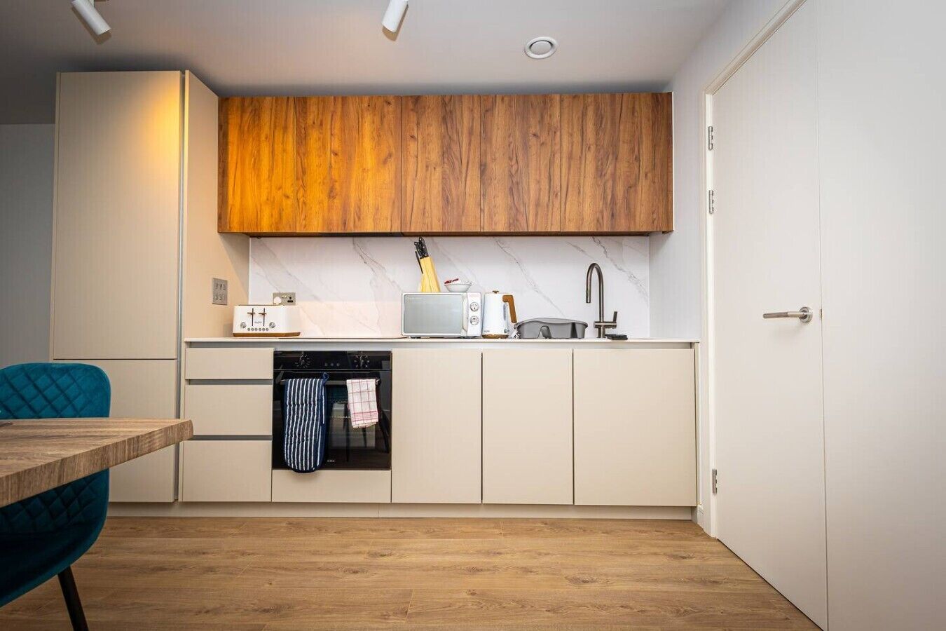 Eine kompakte Küche mit Holzausstattung, einem eingebauten Ofen, einer Mikrowelle und einem Spülbecken.