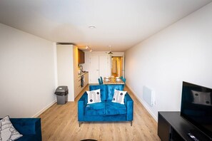 A compact living space with a blue sofa, a dining table, and a television. - Birmingham City Retreat No 126 (Birmingham)