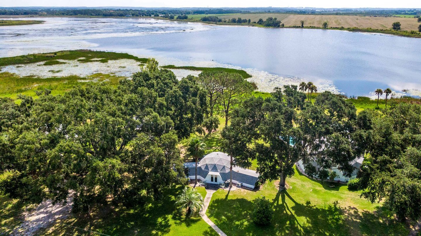 A large body of water with a house surrounded by dense greenery.