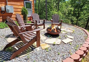 En træterrasse med Adirondack-stole og et bålsted.