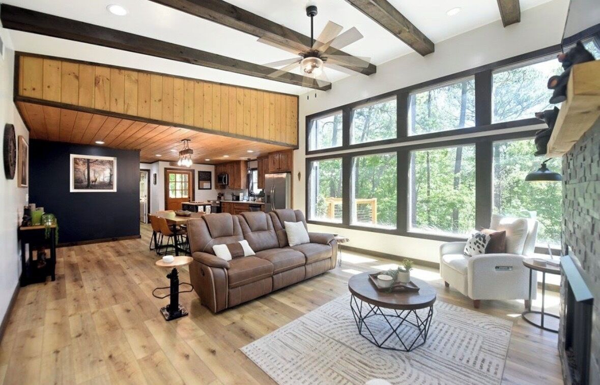 A spacious living area with a large window, a fireplace, and a ceiling fan.