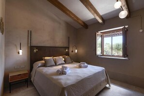 A bedroom with a bed, bedside tables, a window with a view, and wall-mounted lights.