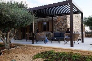 A covered outdoor seating area with stone walls, wicker furniture, and a pergola structure.
