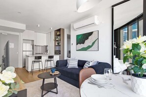 A modern apartment with a kitchen, dining area, and living room. - Luxury CBD Stay, Pool, Spa & City Views (Melbourne)
