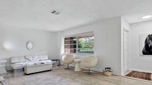 A modern living room with a sofa, chairs, a coffee table, and a large window.