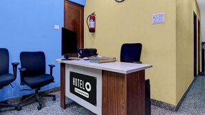 A hotel reception desk with a clock, a fire extinguisher, and a television on the wall. - Deluxe Hotel Bidisha (Kanthi)