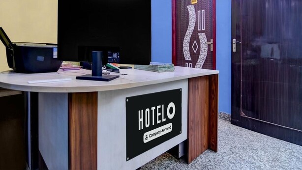 A reception desk with a clock, a closed door with a number, and a sign indicating the hotel is company-serviced. - Deluxe Hotel Bidisha (Kanthi)
