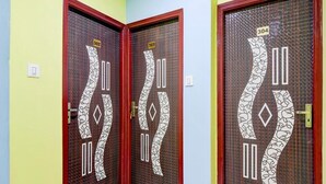 A hallway with three doors, each with a unique pattern and numbered tags. - Deluxe Hotel Bidisha (Kanthi)