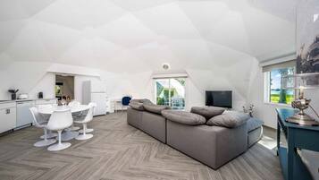 Un appartement moderne de style « loft » comprenant un coin repas, un canapé et un téléviseur.