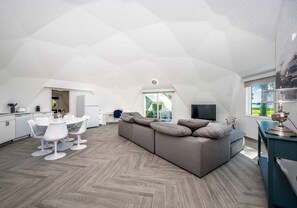Un appartement moderne de style « loft » comprenant un coin repas, un canapé et un téléviseur.