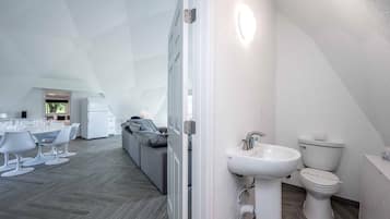 Ein modernes Interieur mit Essbereich, einer Couch und einem Badezimmer mit Waschbecken und Toilette.