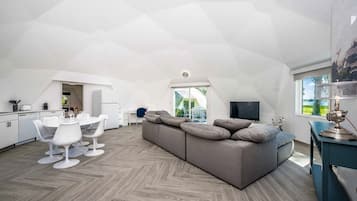 A modern loft apartment with a dining area, a sofa, and a television.