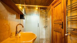 A bathroom with a glass shower enclosure, a wooden cabinet, and a sink with a faucet. - KASTAMONU MAVİ KONAK  (Kastamonu)