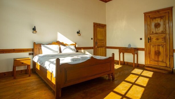 Une chambre à coucher avec un lit en bois, deux tables de chevet, une armoire et une porte.