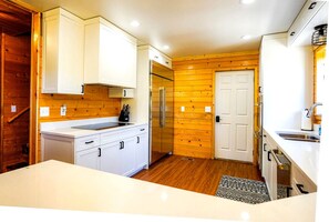 Eine moderne Küche mit weißen Schränken, einem Edelstahlkühlschrank und Holzboden.