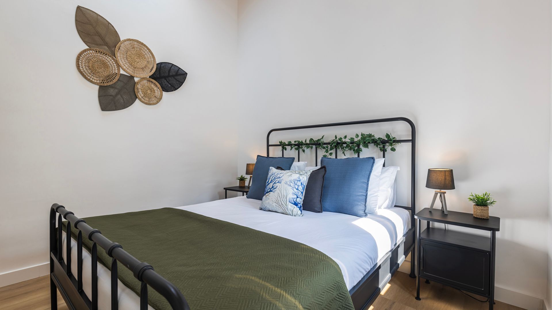 Ein ordentlich eingerichtetes Schlafzimmer mit einem Bett, Kissen, einem Nachttisch mit Lampe und einer Wanddekoration.