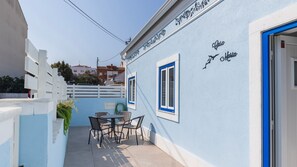 A narrow outdoor patio with a table and chairs, a blue door, and a white fence. - Casa Maria by LovelyStay (Trafaria)