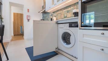Ein moderner Waschraum mit einer Waschmaschine mit Frontlader, einem Trockner und einer gefliesten Spritzschutzwand.