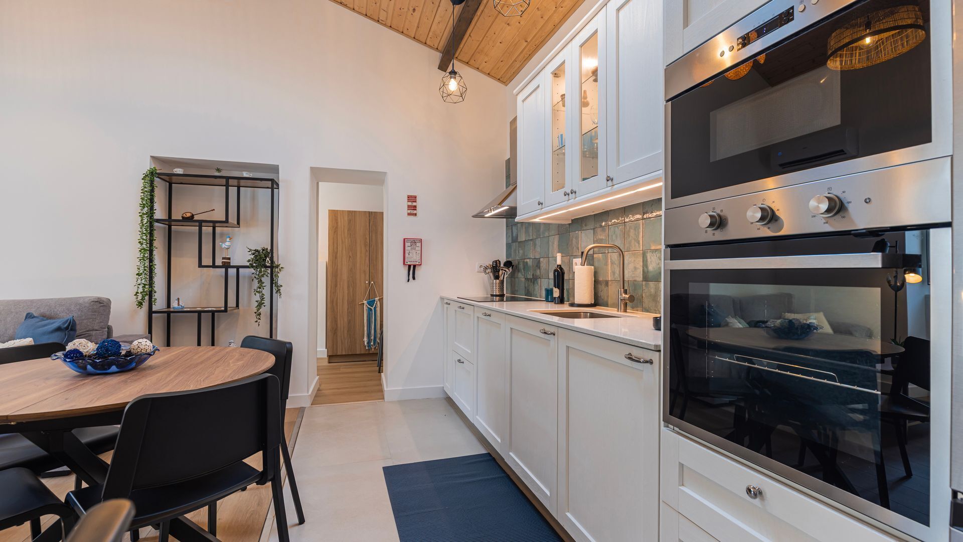 A modern kitchen with white cabinets, stainless steel appliances, and a dining area with a round table and chairs.