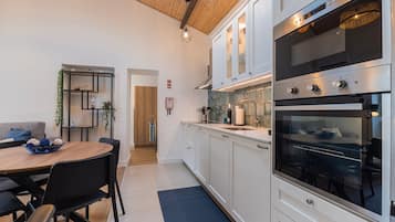 A modern kitchen with white cabinets, stainless steel appliances, and a dining area with a round table and chairs.