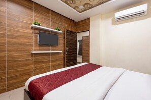 Quarto moderno com uma cama grande, televisão montada e guarda-roupa embutido.