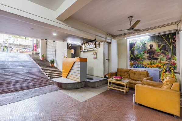 A hotel lobby with a staircase, seating area, and a mural.