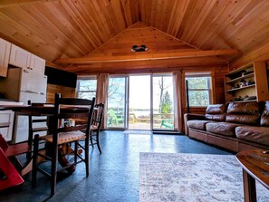 A cabin interior with a dining area, a sofa, and a kitchen. - Incredible Cabin and Cozy Bell Tent by the Lake for a Unique Family Glamping Experience in Eastbrook, Maine (Eastbrook)