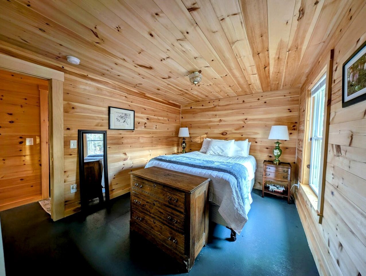 Une chambre à coucher aux murs lambrissés, avec un lit, des tables de chevet et une commode.