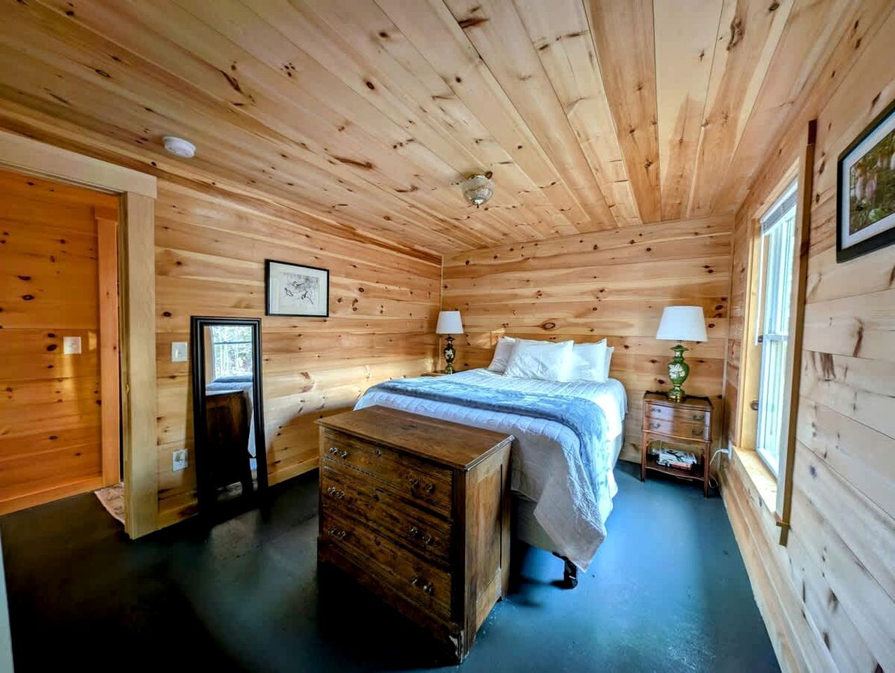 A wooden-paneled bedroom with a bed, bedside tables, and a dresser.