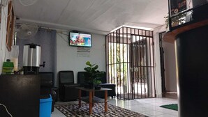 A room with a television, a coffee machine, a desk with a chair, and a potted plant. - Hotel California Santa Ana (Santa Ana)
