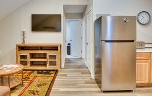 A modern kitchen with a stainless steel refrigerator, a wooden cabinet, and a flat-screen TV mounted on the wall. - Perfect 2-bedroom cabin in delightful Soldotna for a cozy stay (Kasilof)