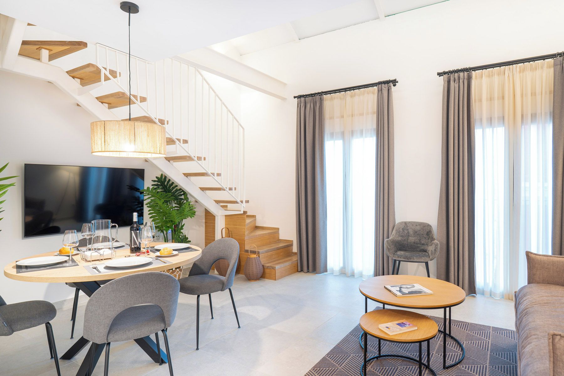 Un salon moderne avec un escalier, un coin repas et un espace détente.