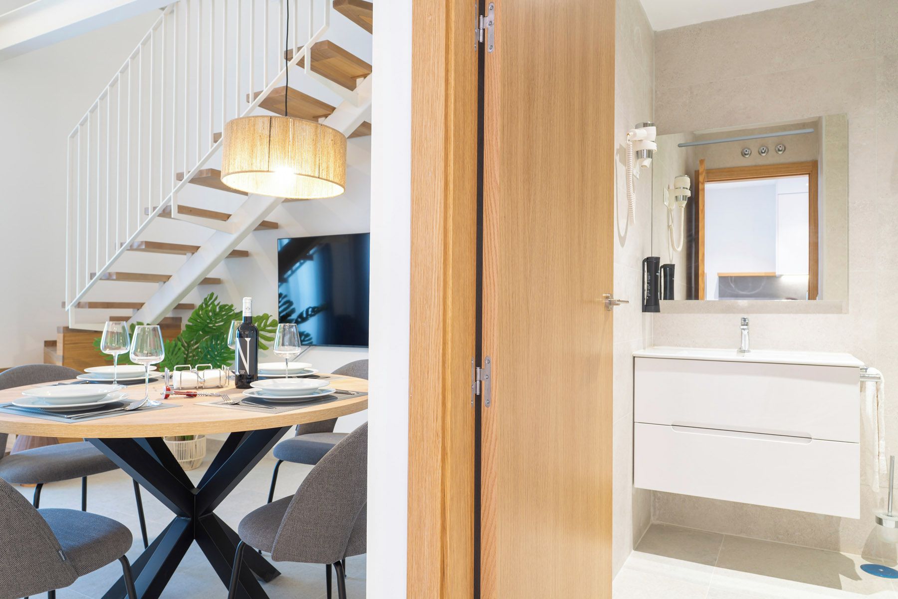 Un espace repas moderne avec une table en bois, des chaises et un luminaire suspendu.