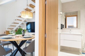 Ein zeitgemäßer Essbereich mit Holztisch, Stühlen und einer Hängeleuchte.
