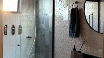 A modern bathroom with a glass-enclosed shower, a white toilet, and a black sink with a mirror above.