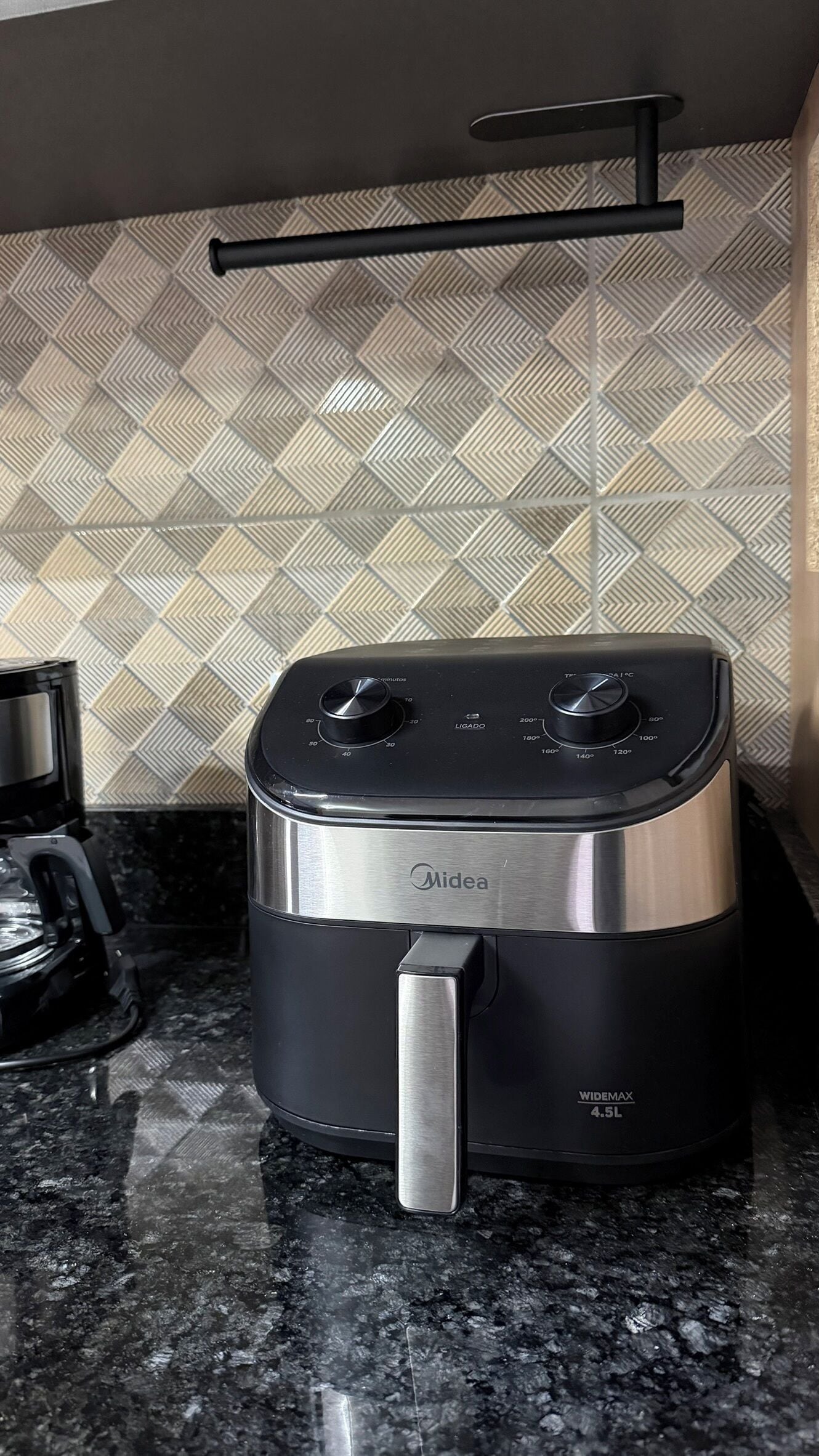 Una freidora de aire Midea sobre una encimera de granito con un salpicadero de diseño de rombos.