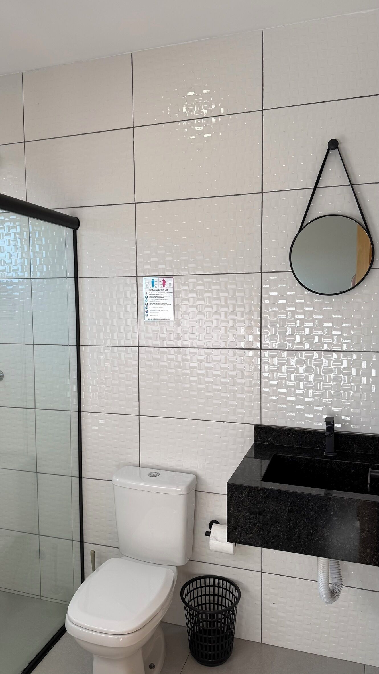 Une salle de bain équipée de toilettes, d’un lavabo, d’un miroir et d’un sèche-mains.