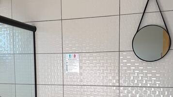 Une salle de bain équipée de toilettes, d’un lavabo, d’un miroir et d’un sèche-mains.