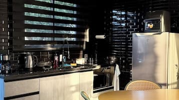 A modern kitchen with a central island, black cabinetry, and a dining area with rattan chairs.