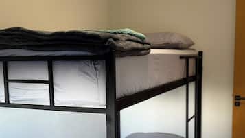 A bunk bed with a wooden ladder, a small stool, and a door in the background.