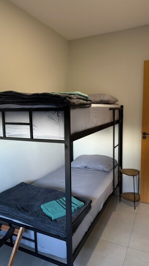 A bunk bed with a wooden ladder, a small stool, and a door in the background.