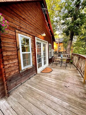 A wooden cabin with a deck, a table with chairs, and a door.