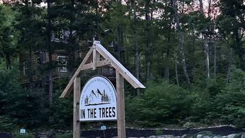 A wooden sign with the text 'IN THE TREES' and a mountain graphic, indicating a mountain-related attraction.