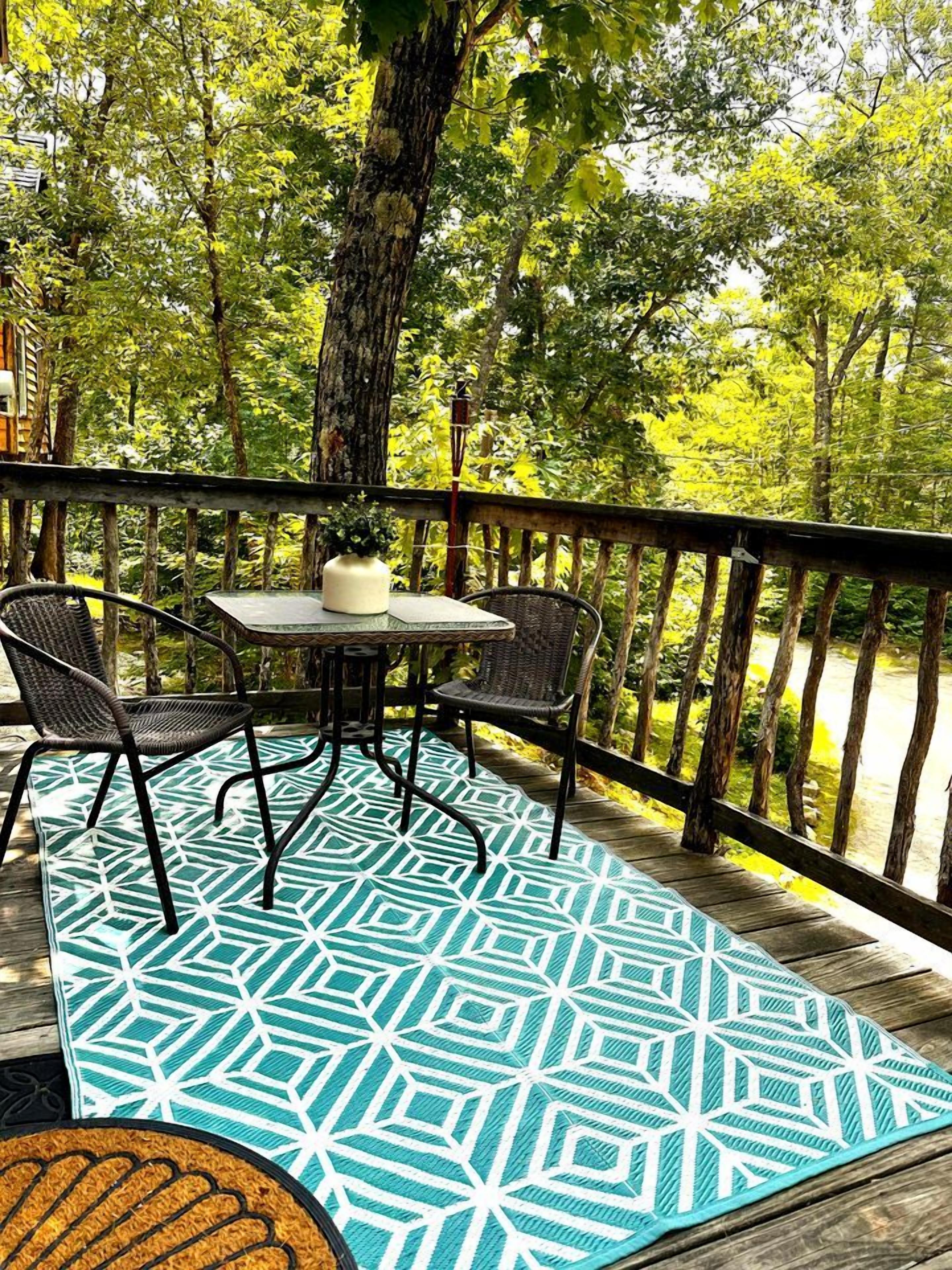 A wooden deck with a table and chairs, surrounded by trees.