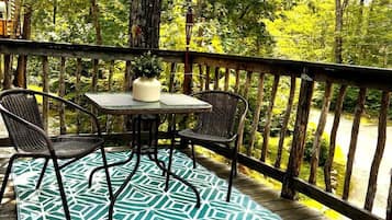 A wooden deck with a table and chairs, surrounded by trees.